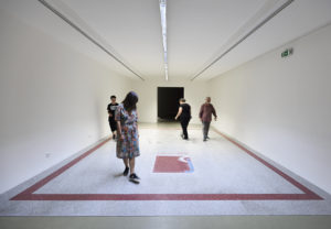 People walking around a rectangle on the floor.