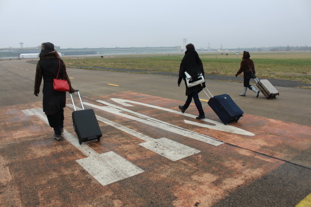 Three women with suitcases walking down a runway
