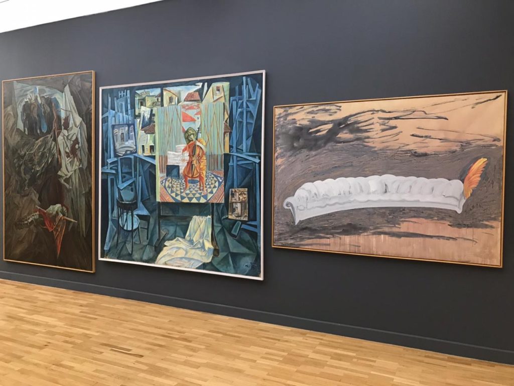 view of three paintings hung on a gray wall, works by Edi Rama, Ardian Paci, Edi Muka, and Edi Hila