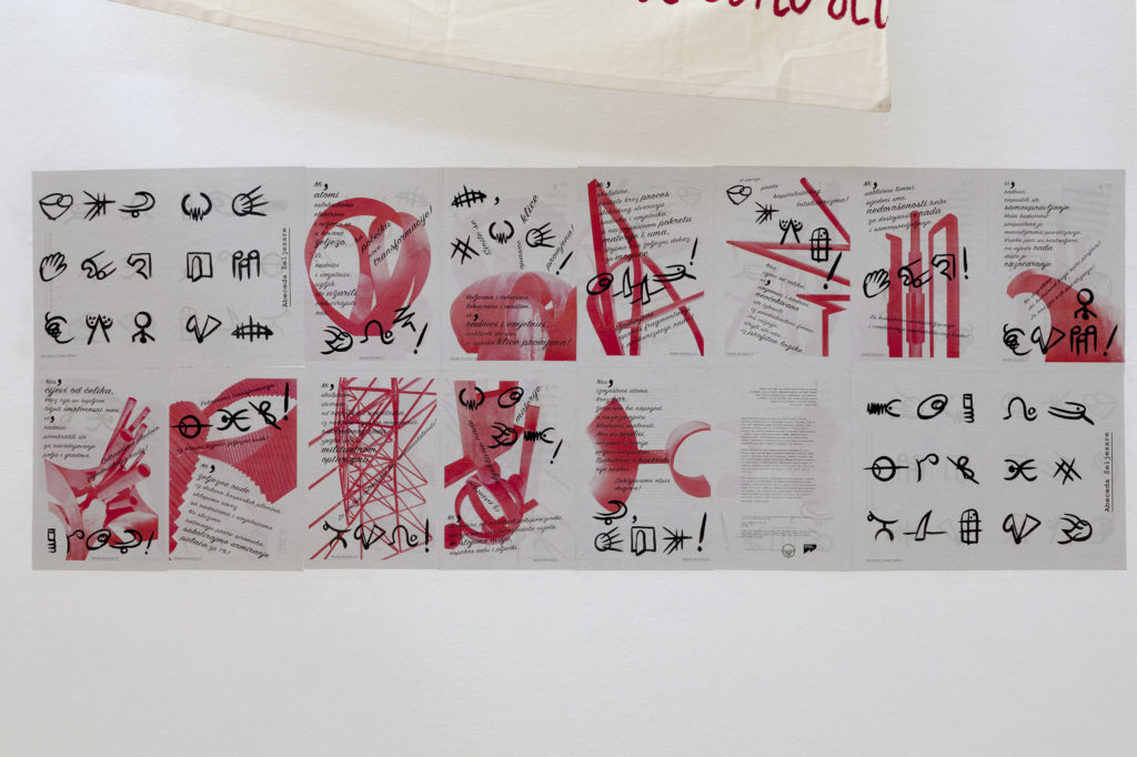 A newspaper wall installation displays red and black symbols and texts