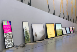 Nine electronic panels leaning against a wall, each showing a different colourful image.