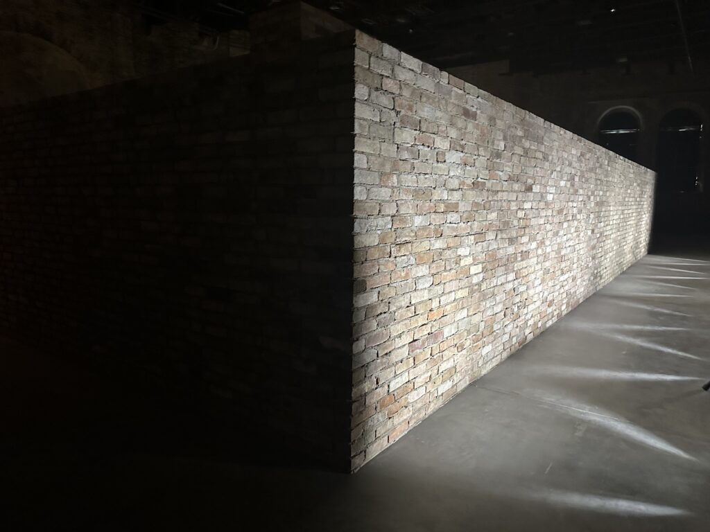 A brightly lit section of brick wall, positioned at an angle to the viewer, while a perpendicular section at left is completely dark, thrown into shadow.