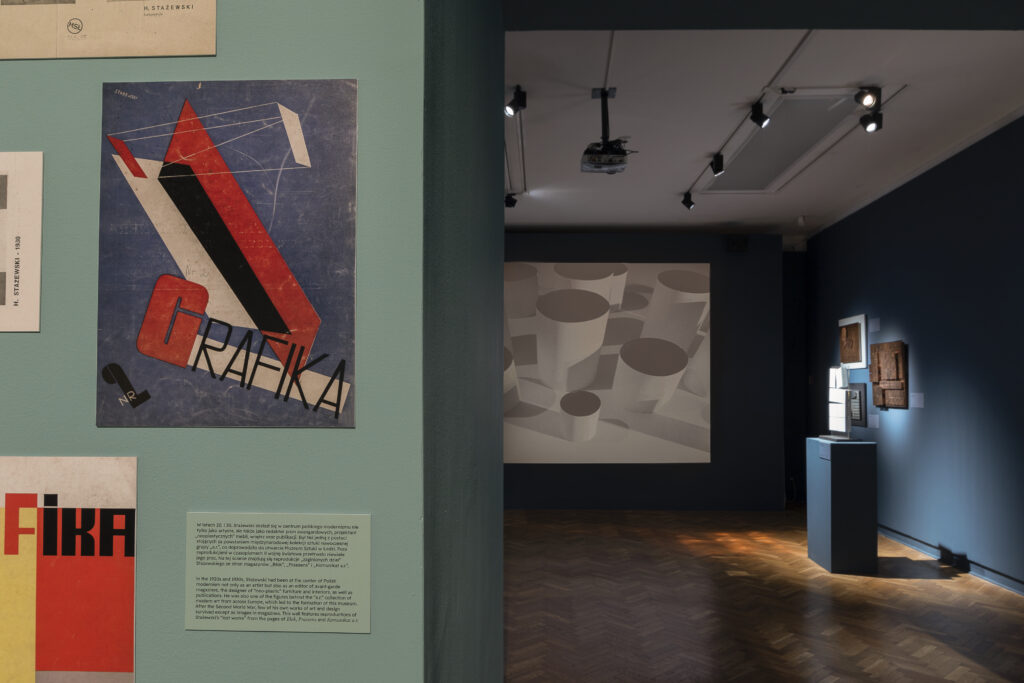 Room within the Henryk Stażewski exhibition displaying works of sculpture and graphic design.