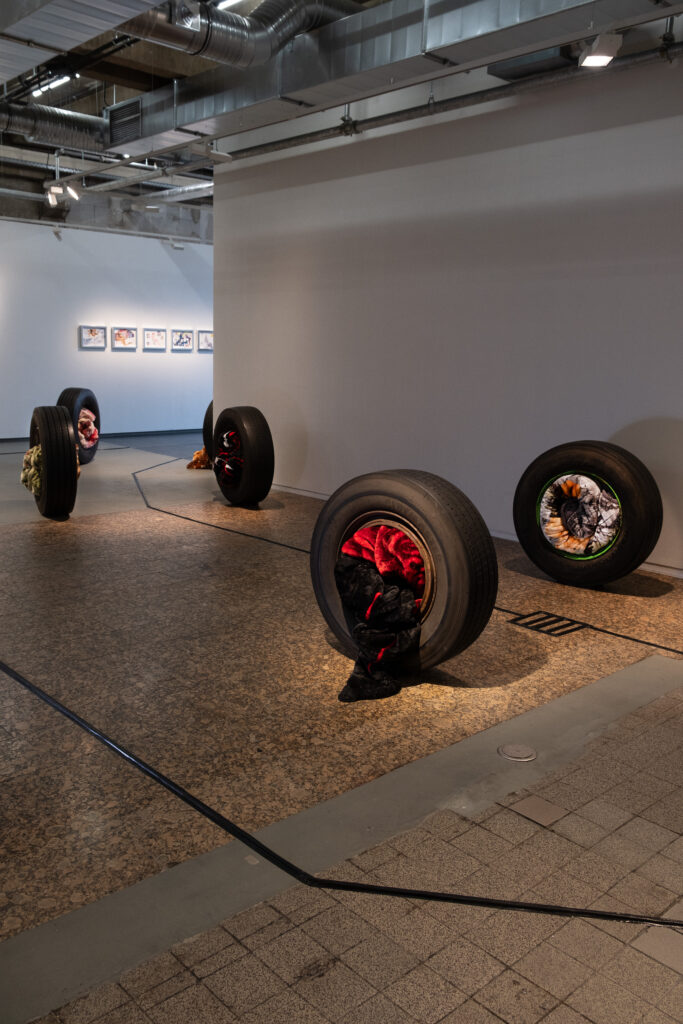 A series of rubber tires holding synthetic blankets symbolizing traveling home.